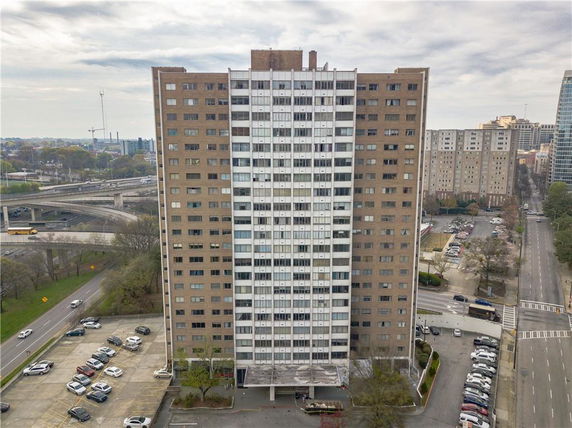 Front view of a high-rise building with numerous windows and a surrounding road network.