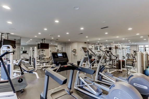 Indoor gym area with various exercise equipment and machines.