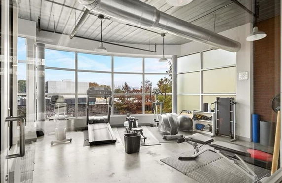 Indoor gym area with exercise equipment and large windows.