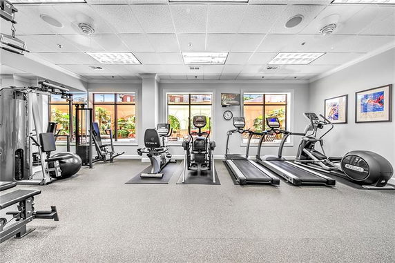 Indoor gym area with various exercise equipment and large windows.