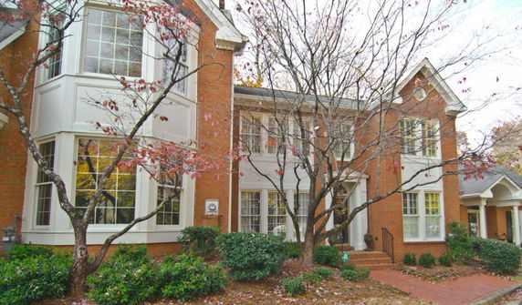 Front view of a two-story brick house with multiple large windows and a small porch.