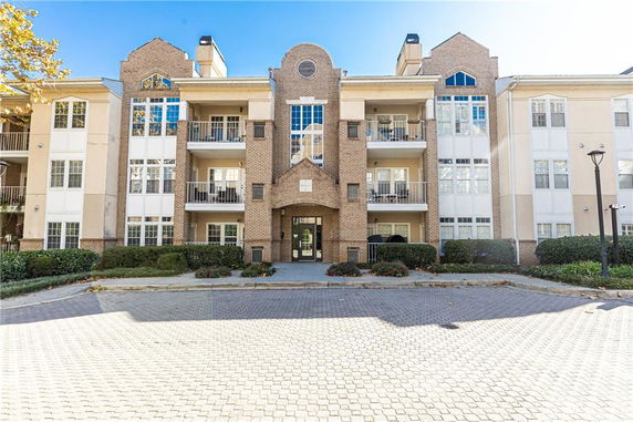 Front view of a multi-story apartment building with brick and beige facade.