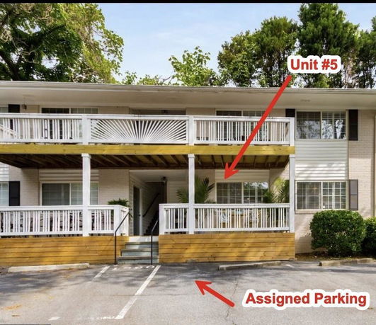 Front view of a multi-story residential building with balconies and parking area.