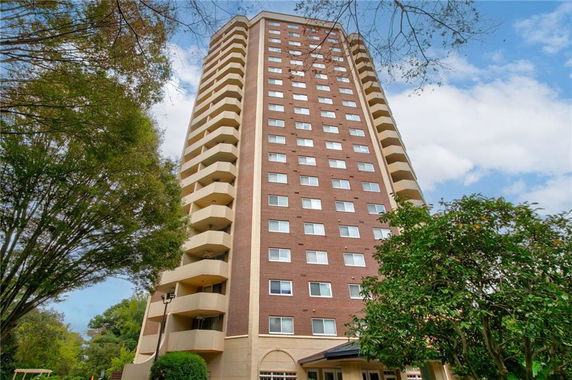 Front view of a tall residential building with multiple floors and balconies.