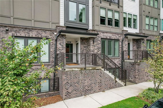 Front view of a multi-story brick townhouse with steps leading to the entrance.