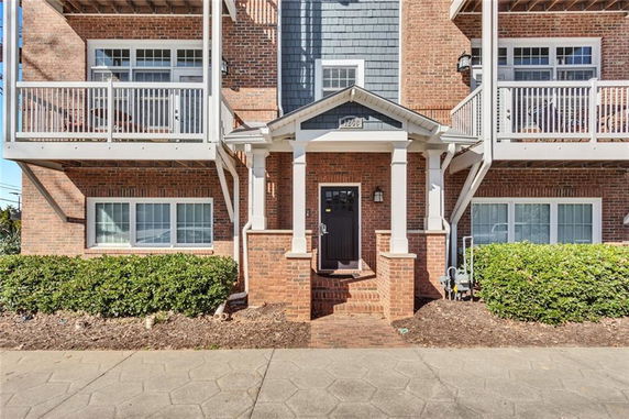 Front view of a multi-story brick building with balconies and a central entrance.