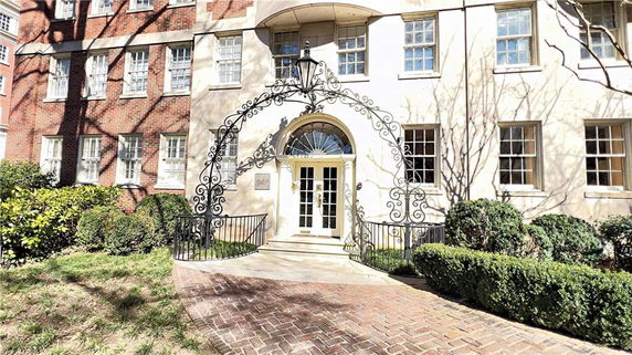 Front view of a brick building with decorative ironwork above the entrance.