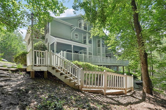 Side view of a two-story house with a large deck and surrounding trees.