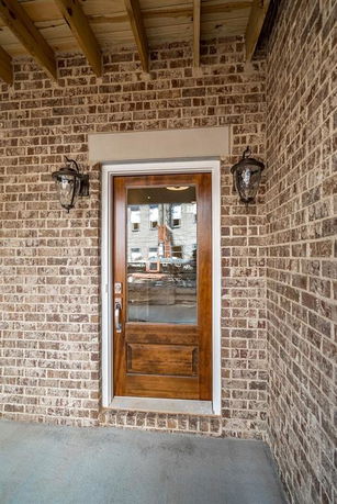 Front view of a house entrance with a wooden door and brick exterior.