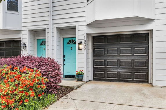Front view of house with attached garage and blue front door.