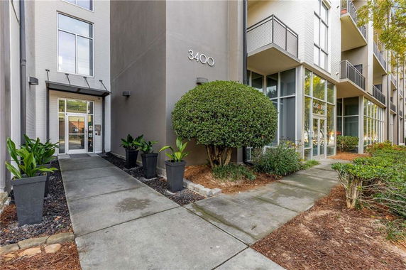 Front view of a modern building entrance with large windows and potted plants.