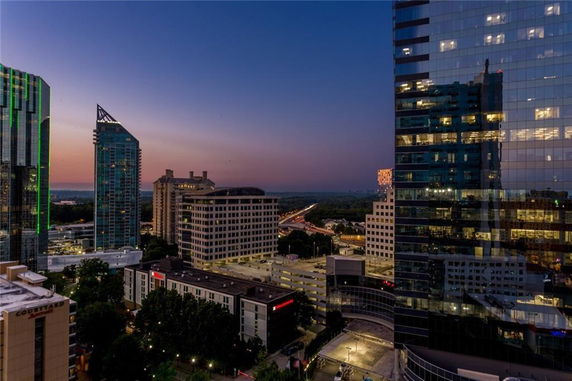 Panoramic view of cityscape with tall buildings and highway at dusk.