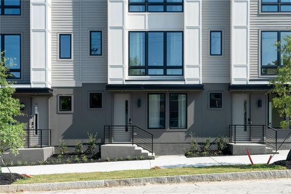 Front view of a modern multi-story townhouse with large windows and steps leading to the entrance.