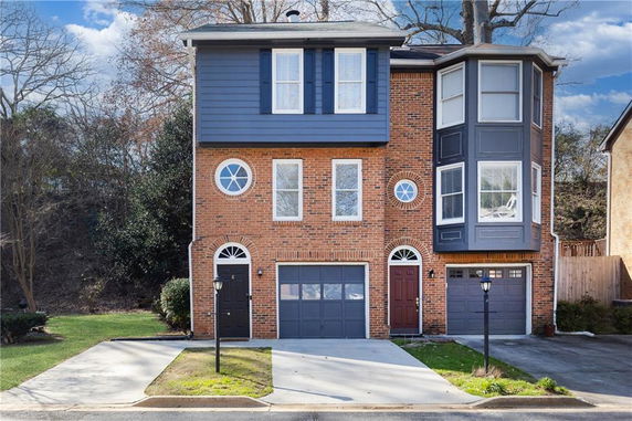 Front view of a three-story brick house with a single garage and bay windows.