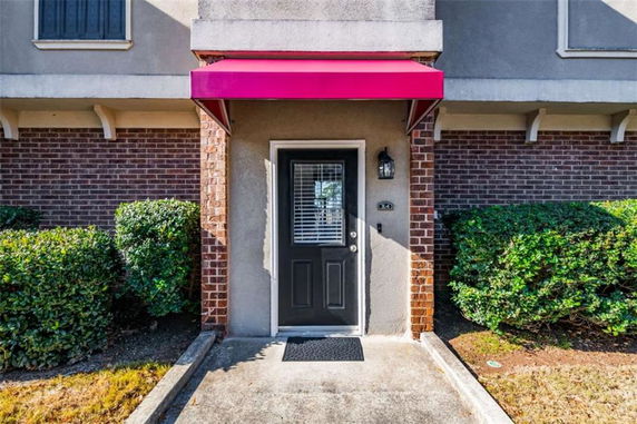 Front view of a building entrance with a red awning and brick facade.