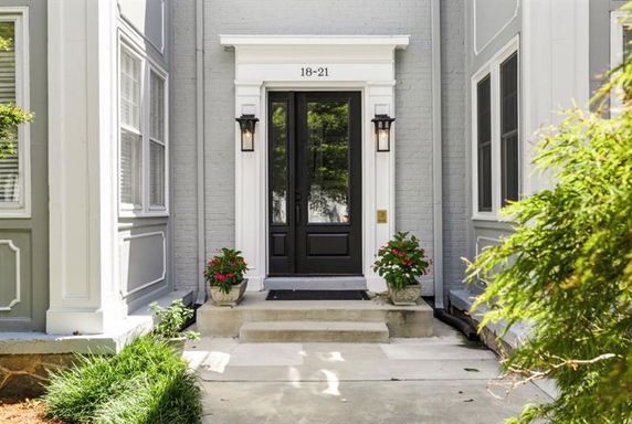 Front view of a house with a black door and decorative white trim.