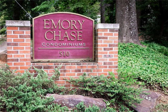 Sign for Emory Chase Condominiums with brick and greenery.