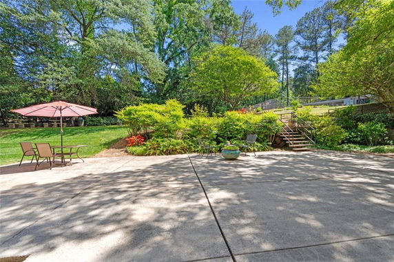 View of a spacious patio area with outdoor furniture and lush greenery in the background.