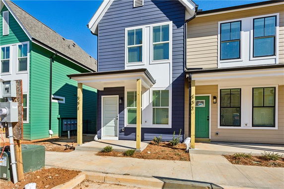 Front view of a two-story townhouse with a covered porch and modern design.