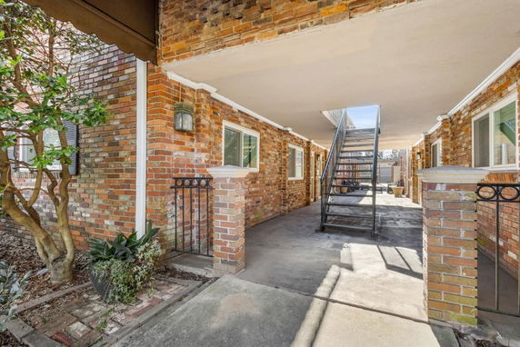View of brick exterior building with an open corridor and stairway access.