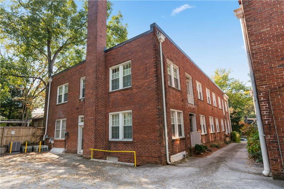Front view of a two-story brick building with multiple windows and a chimney.