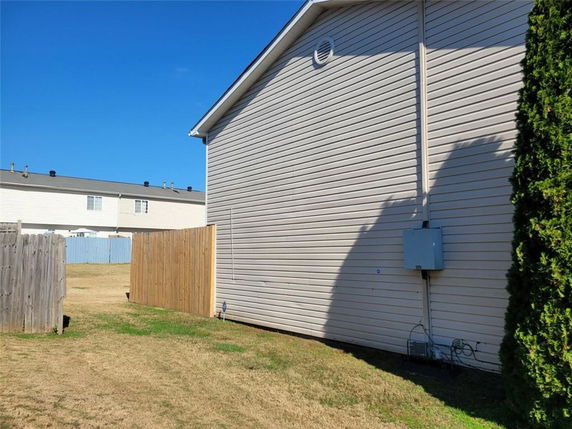 Side view of a house with beige siding and a small electrical box.