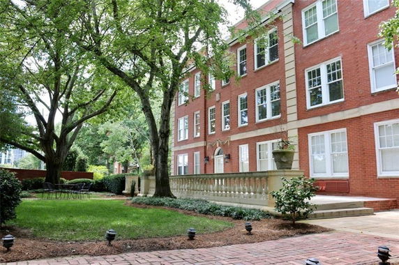Front view of a three-story brick building with multiple windows and a landscaped garden area.