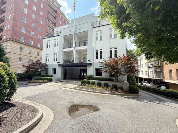 Front view of a multi-story white building with a covered entrance and balconies.