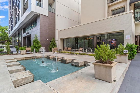 Front view of a modern building with a water fountain in the foreground.