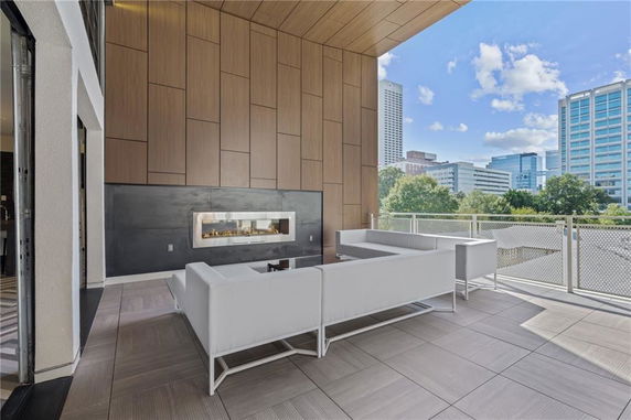 Rooftop seating area with modern furniture and a fireplace, overlooking city buildings.