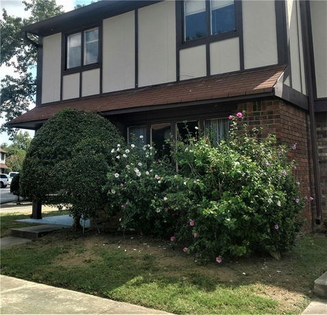 Front view of a two-story house with Tudor-style architecture and a small garden.