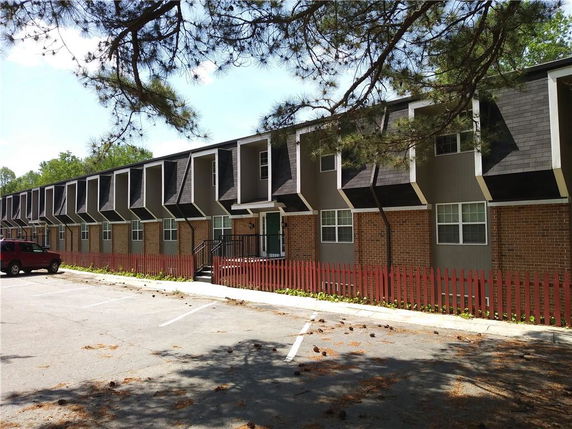 Front view of a two-story apartment building with brick facade and angled roof extensions.