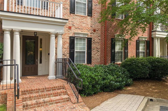 Front view of a two-story brick house with columns and a balcony.