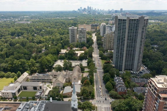 Panoramic view of urban and suburban landscape with high-rise buildings, streets, and green areas.