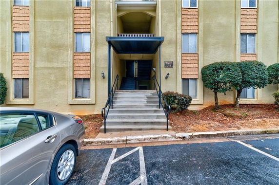 Front view of a multi-story apartment building entrance with stairs leading up.