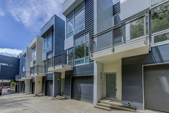 Front view of a modern multi-story residential building with balconies and garages.
