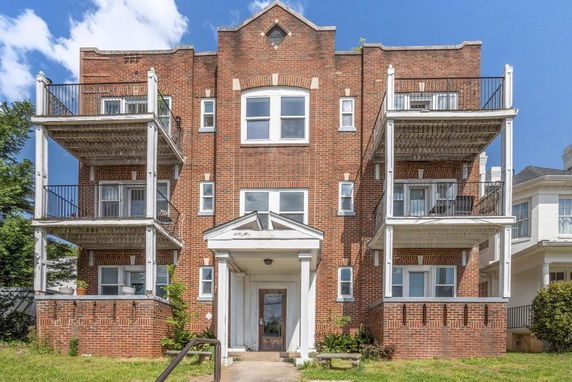 Front view of a multi-story brick building with balconies on each side.