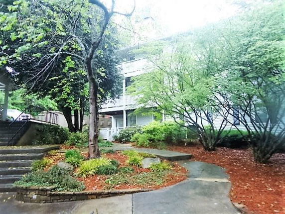 Front view of a multi-story building with a pathway and greenery.