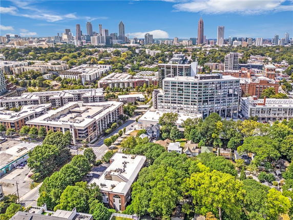 Panoramic view of a cityscape with various residential and commercial buildings, surrounded by greenery.