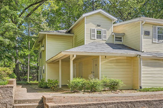 Front view of a two-story house with beige siding and a covered entryway.