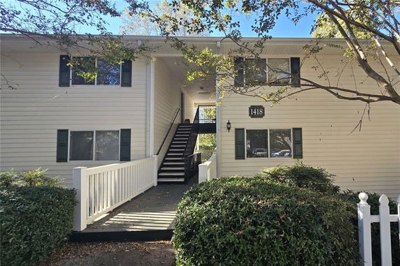 Front view of a two-story building with stairs and a white railing.