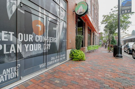 Street view of a brick building with outdoor seating and storefronts.