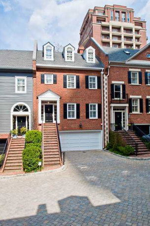 Front view of a multi-story townhouse with red brick facade and white accents.