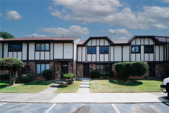 Front view of a two-story townhouse with a brick facade and dark trim.