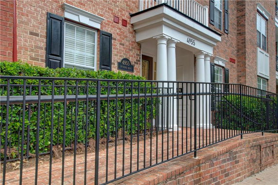 Front view of a brick building with columns and black shutters.