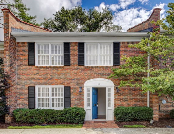 Front view of a two-story brick house with a blue door and white-framed windows.