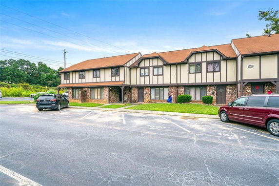 Front view of two-story townhouse building with pitched roofs and parking area.