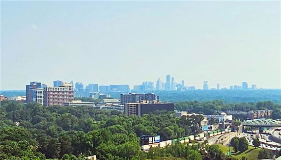 Panoramic view of a city skyline with surrounding greenery and roads.