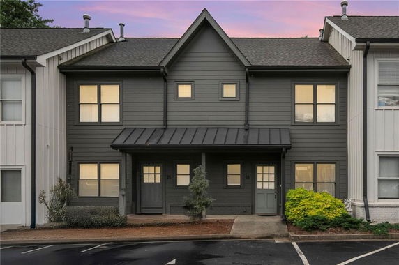 Front view of a two-story townhouse with a dark exterior and gabled roof.