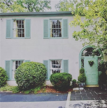 Front view of a two-story house with green shutters and door.